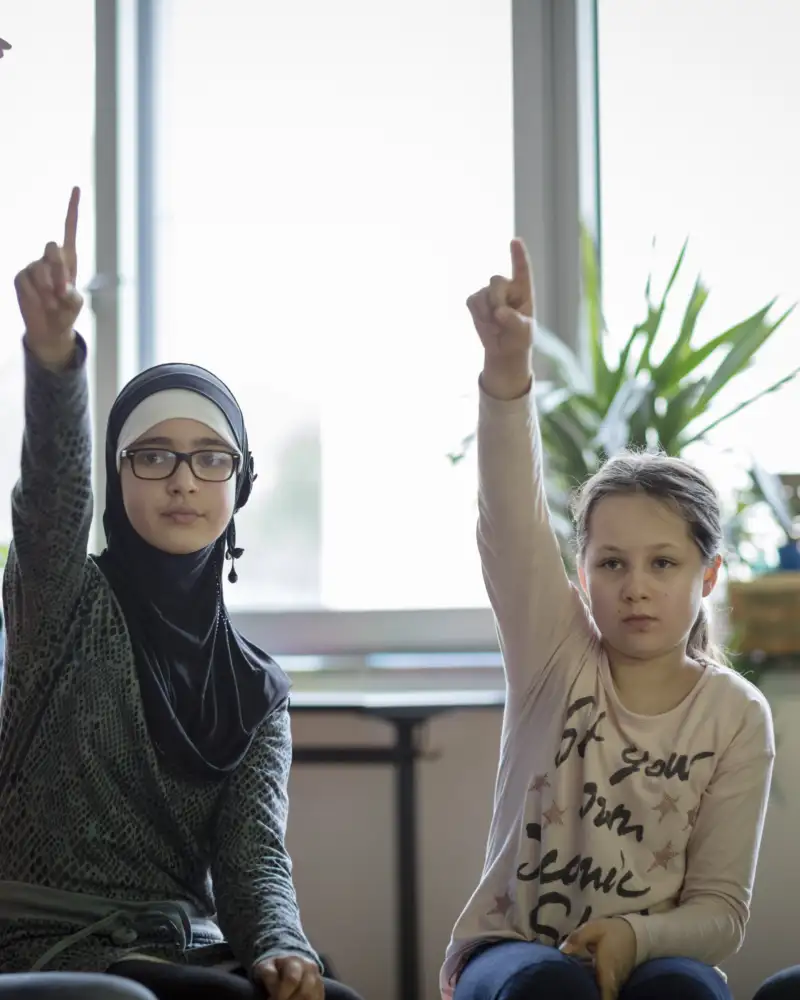 Mehrere Kinder melden sich im Unterricht
