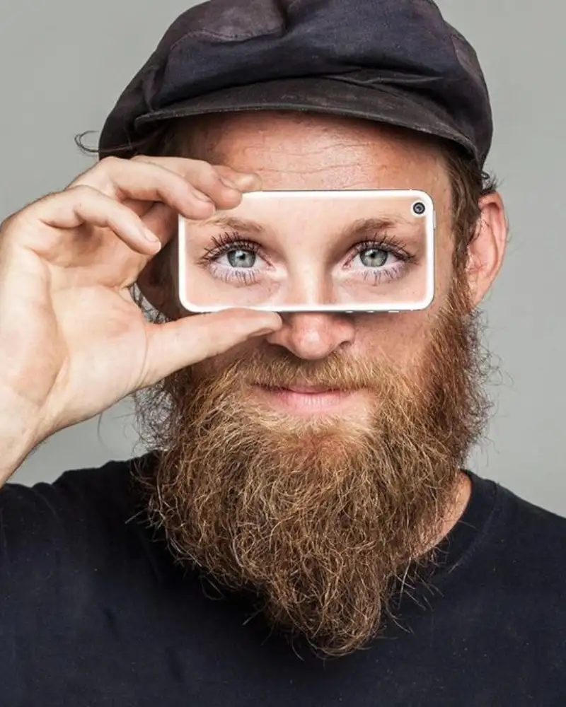 Ein mann hält sich ein Handy vor die Augen. Seine Augenpartie ist durch das Handy zu sehen.
