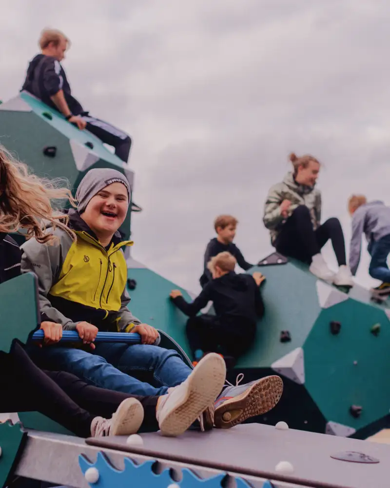 Besucher des inklusiven barrierefreien Spielplatzes im Mehrgenerationenpark in Timmel testen die Wippe und (im Hintergrund) das neue Klettergerüst.