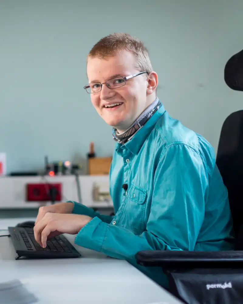 Ein Mann im Rollstuhl arbeitet am Computer.