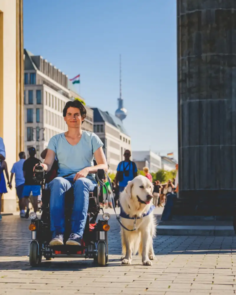 Barrierefreiheit und Tourismus in Berlin. Eine frau im Rollstuhl vor dem Brandenburger Tor.