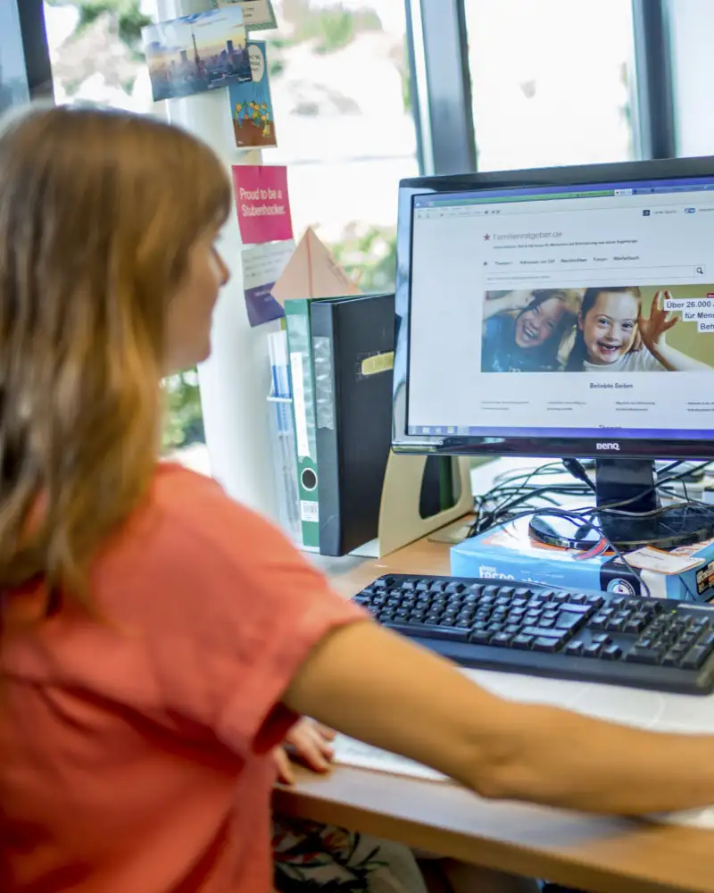 Eine Frau sitzt an einem Computer und schaut auf den Bildschirm.