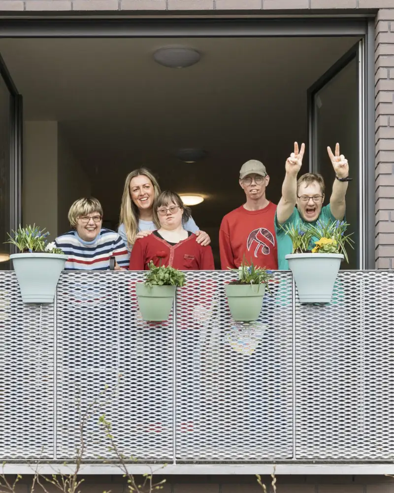 Die Teilnehmer der inklusiven WG in Braunschweig mit ihrer Stadtteillotsinwinken vom Balkon ihrer neuen Wohnung.