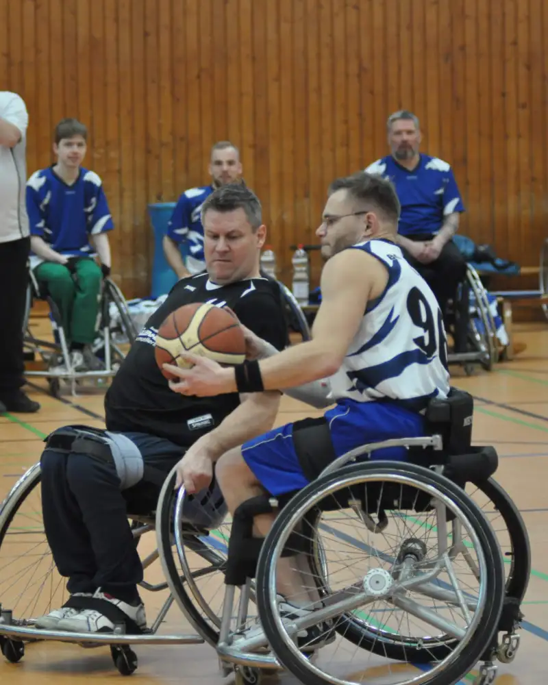 Zwei Männer spielen Rollstuhlbasketball.