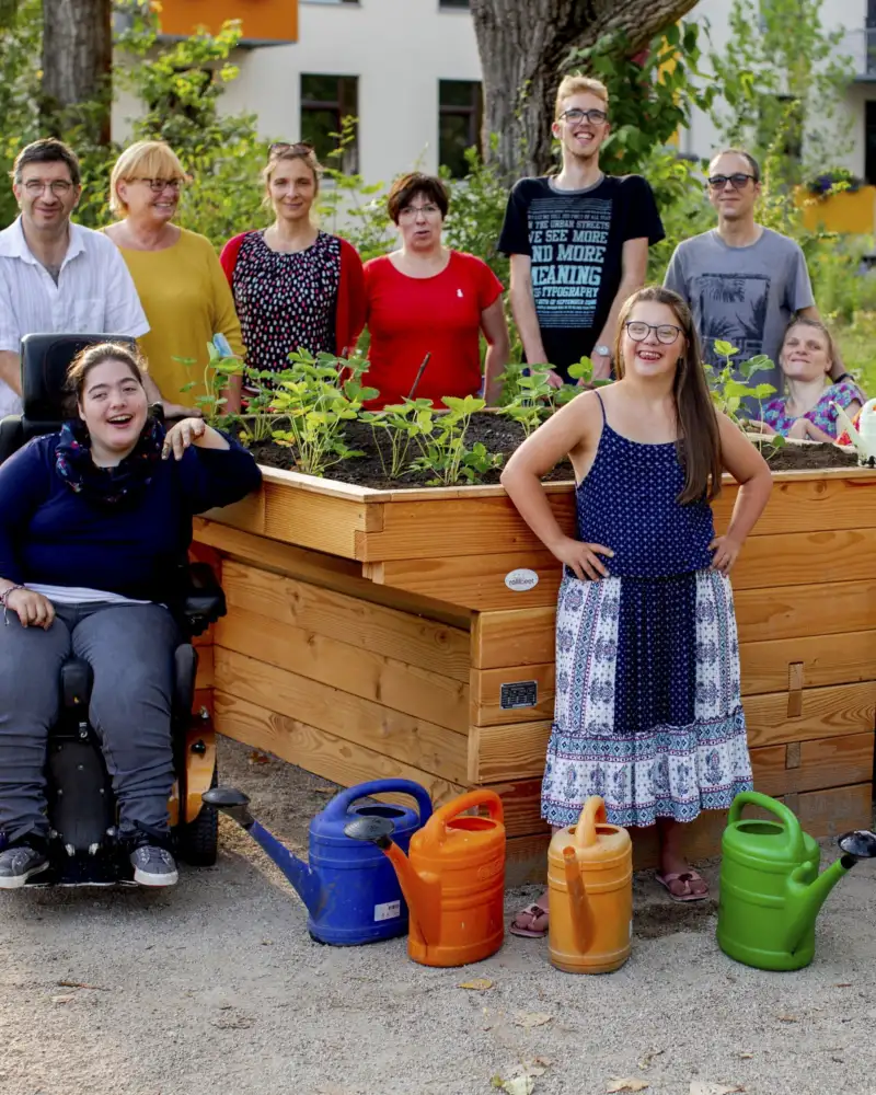 Die Bewohner der Wohngemeinschaft RO 70 in Weimar mit ihren Gartenwerkzeugen vor einem neuen rollstuhlgerechten Hochbeet.
