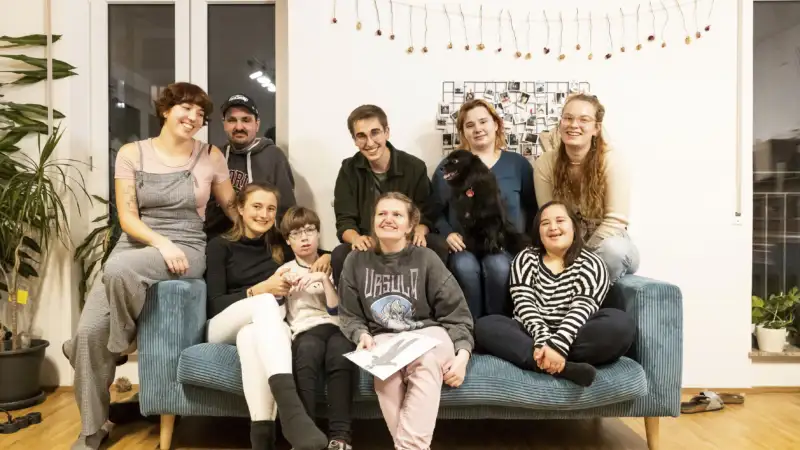 Eine Gruppe von Menschen mit und ohne Behinderung sitzt gemeinsam auf einem Sofa