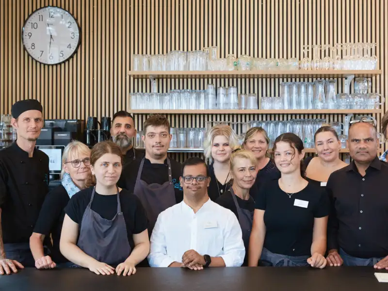 Eine Gruppe von unterschiedlichen Menschen, die in einem Café arbeiten.
