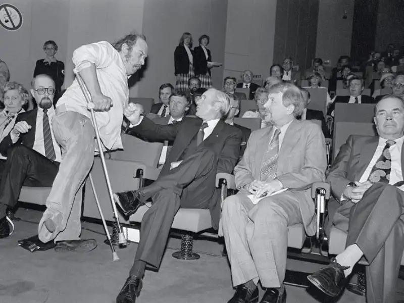 Franz Christoph, Aktivist der „Krüppelbewegung“, schlägt Bundespräsident Karl Carstens bei Eröffnung der Reha-Messe 1981 in Düsseldorf mit seiner Krücke ans Schienbein.