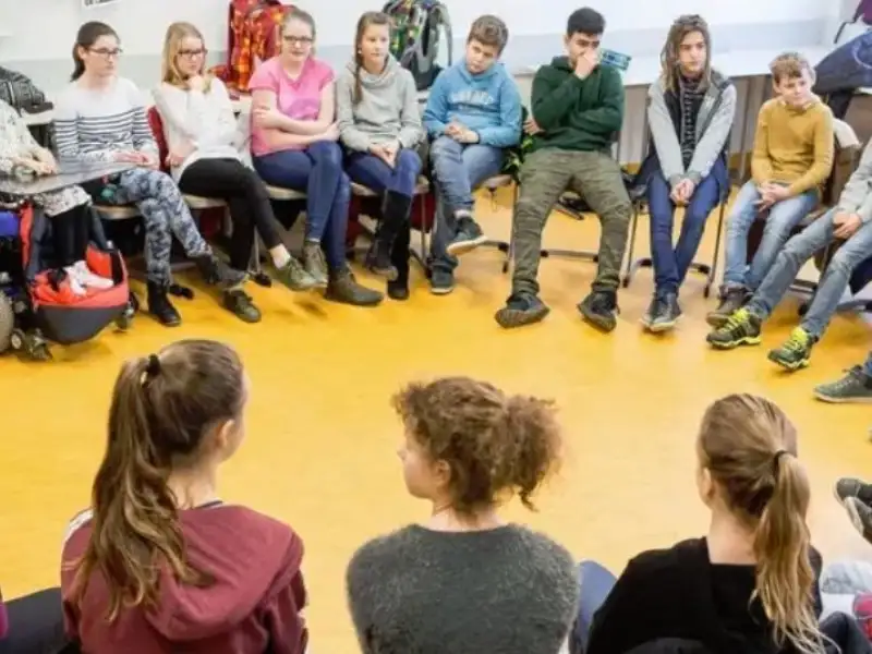Eine große Gruppe von Schülerinnen und Schülern sitzt zusammen in einem Stuhlkreis.