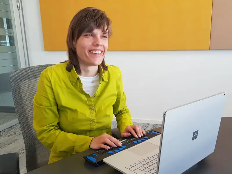 Franziska Sgoff arbeitet mit einer Braillezeile an einem Laptop-Computer.