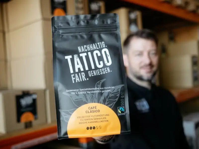 Der Geschäftsführer der Röstwerkstatt, Thorsten Schulz, hält eine Packung des tatico-Kaffees vor sich.