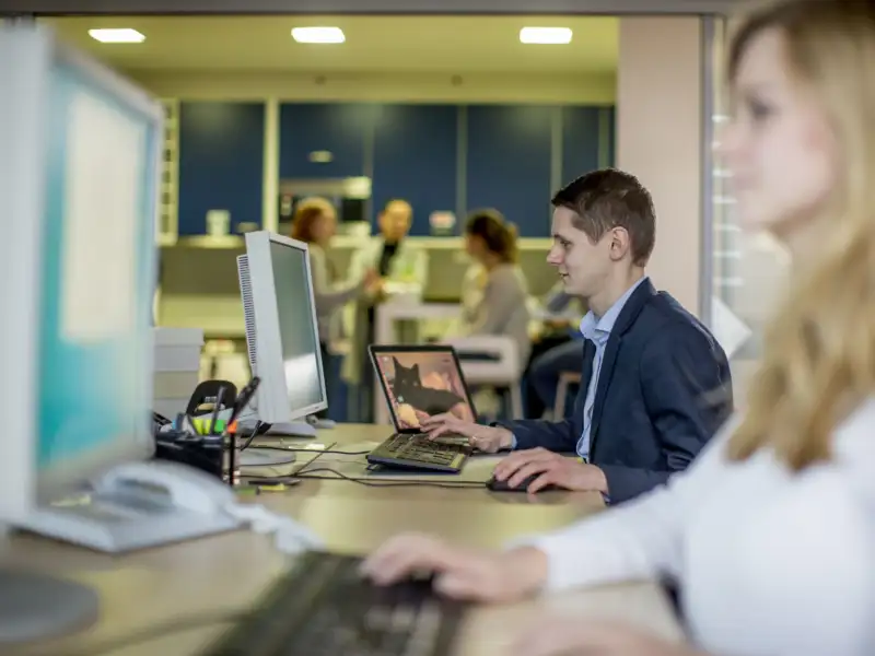Ein junger Mann und eine junge Frau schauen auf den Computer-Bildschirm.