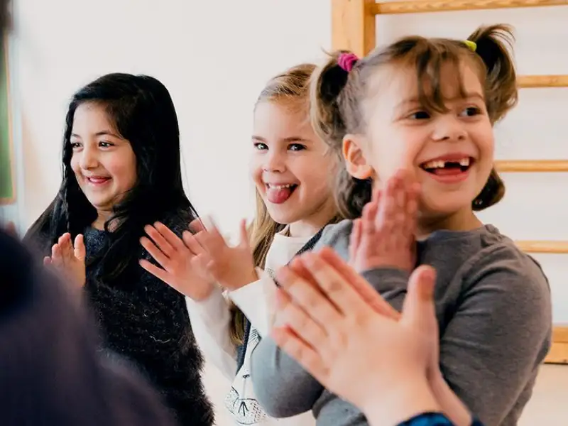 Mehrere Kinder stehen nebeneinander und klatschen in die Hände.