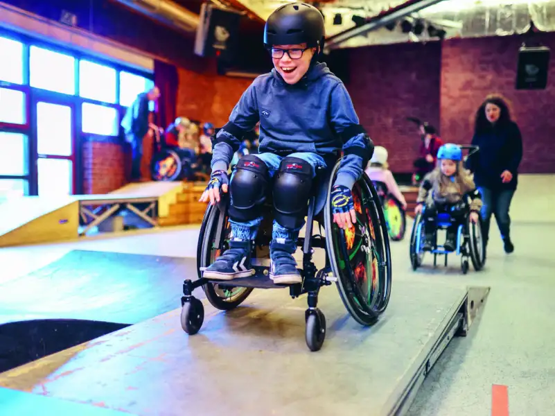 Ein Junge im Rollstuhl fährt über eine Skatebahn