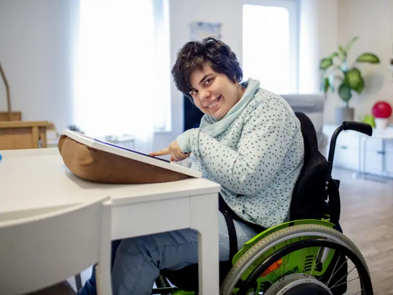 Eine Frau im Rollstuhl bedient zu Hause ein Tablet