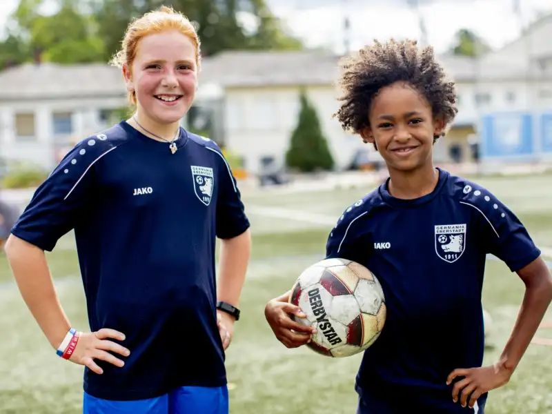 Zwei Jugendliche in blauen Trikots und einem Fußball