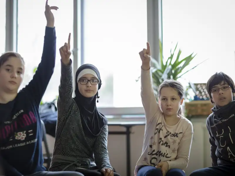 Mehrere Kinder melden sich im Unterricht