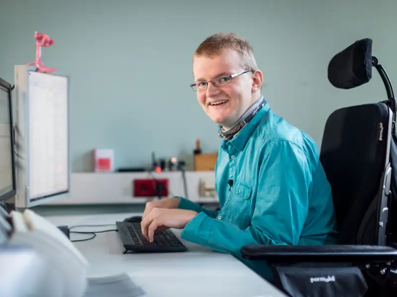 Ein Mann im Rollstuhl arbeitet am Computer.