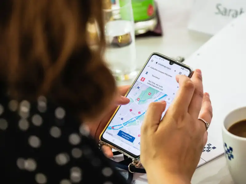 Eine Hand hält ein Handy in der Hand, auf dem Bildschirm ist die Wheelmap App geöffnet.