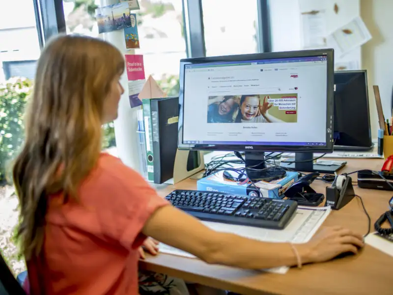 Eine Frau sitzt an einem Computer und schaut auf den Bildschirm.
