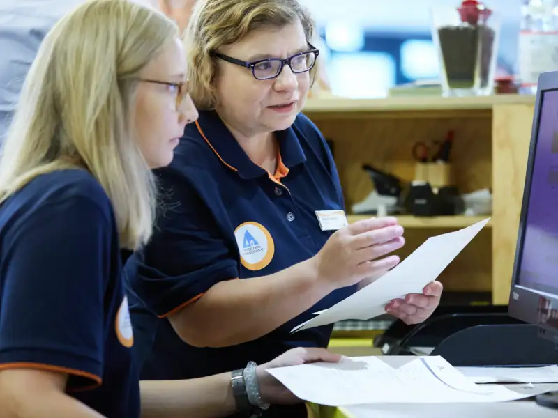 Zwei Frauen sitzen vor einem Computer und schauen gemeinsam auf den Bildschirm.