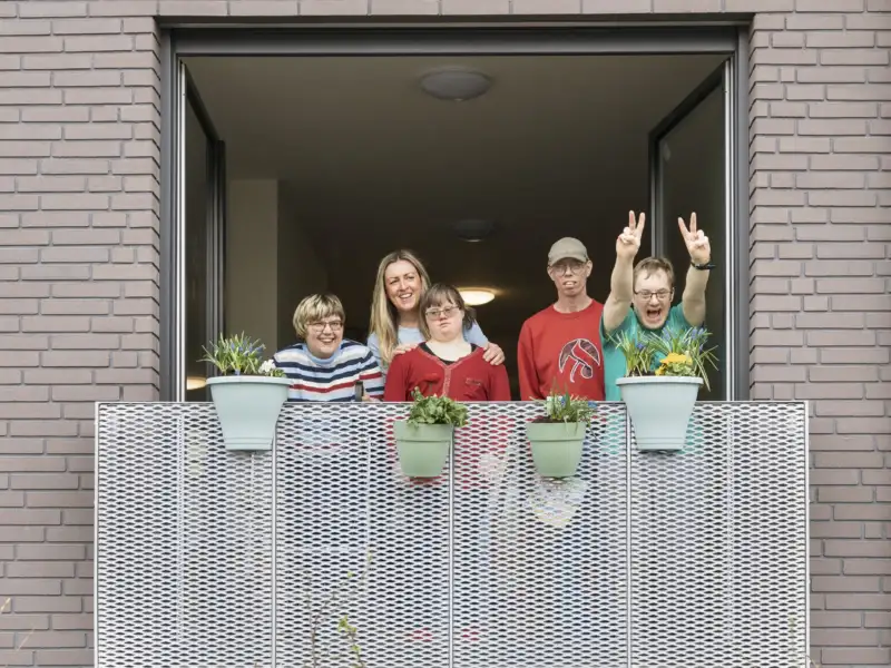 Die Teilnehmer der inklusiven WG in Braunschweig mit ihrer Stadtteillotsinwinken vom Balkon ihrer neuen Wohnung.