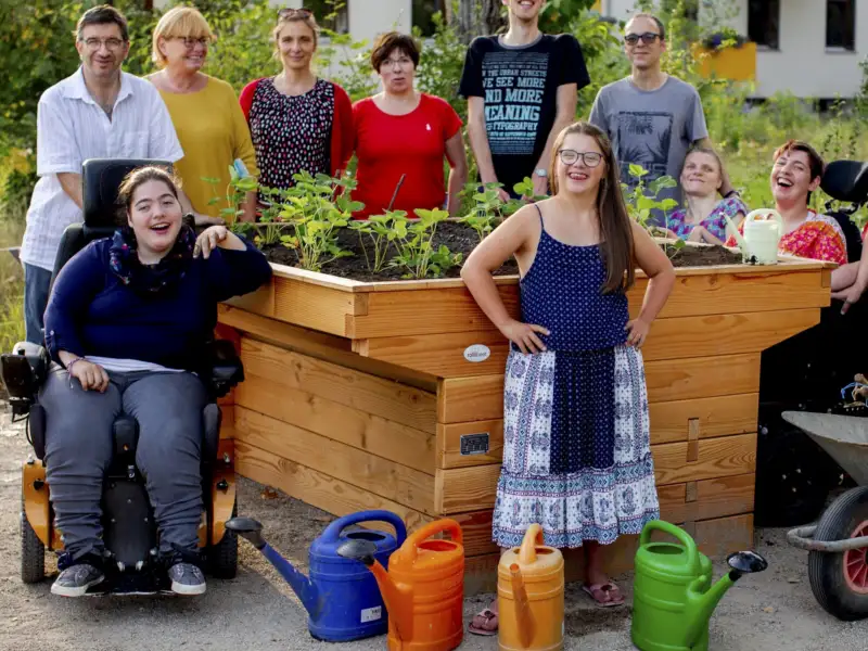Die Bewohner der Wohngemeinschaft RO 70 in Weimar mit ihren Gartenwerkzeugen vor einem neuen rollstuhlgerechten Hochbeet.