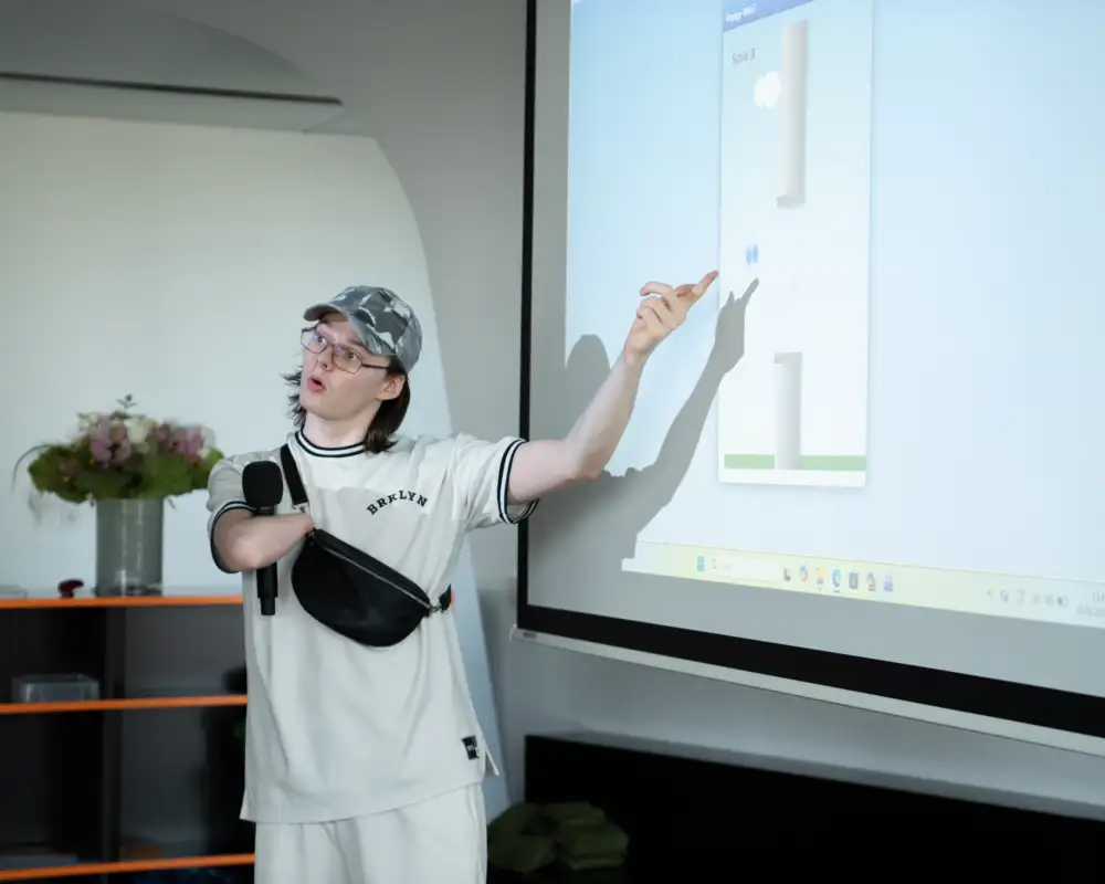 Ein Jugendlicher mit Behinderung steht vor einer Leinwand und präsentiert etwas.