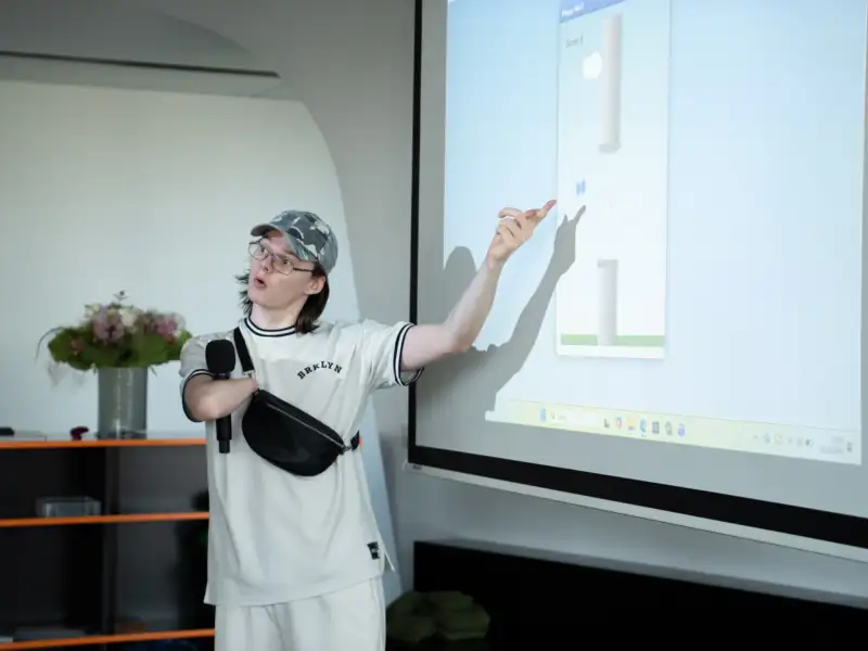 Ein Jugendlicher mit Behinderung steht vor einer Leinwand und präsentiert etwas.