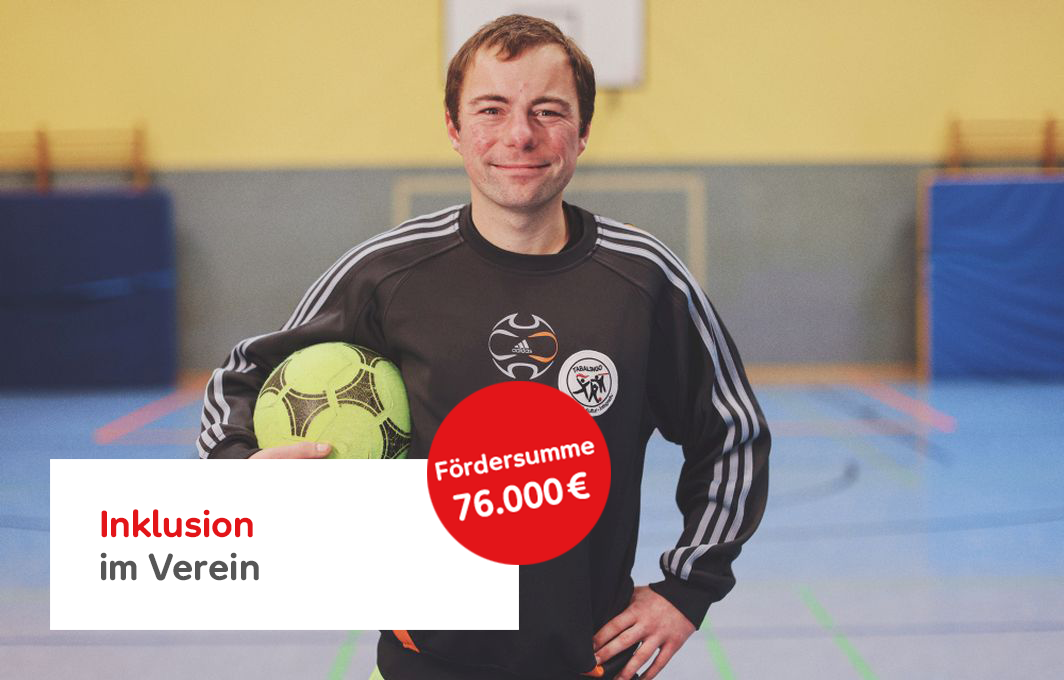 Der Trainer Eric hält einen Ball im Arm und grinst in die Kamera. Davor der Hinweistext "Inklusion im Fußballtraining, Fördersumme 76.000 €"