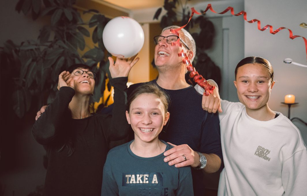 Jörgs Familie jubelt mit Luftballons und Luftschlangen.