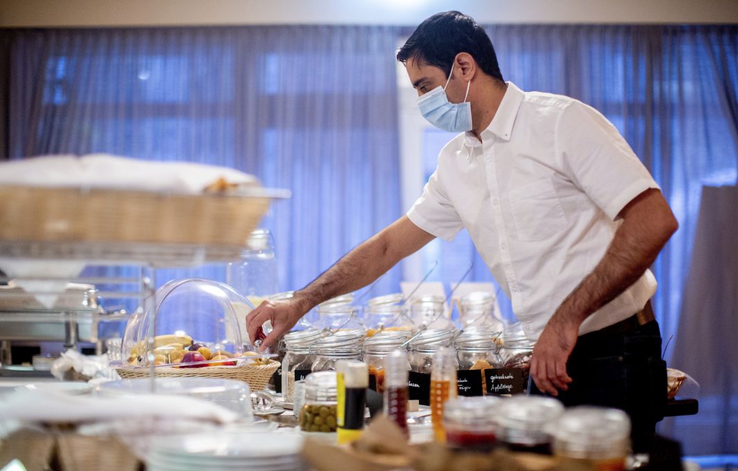 Ein Mitarbeiter sortiert die Gläser am Frühstücksbuffet.