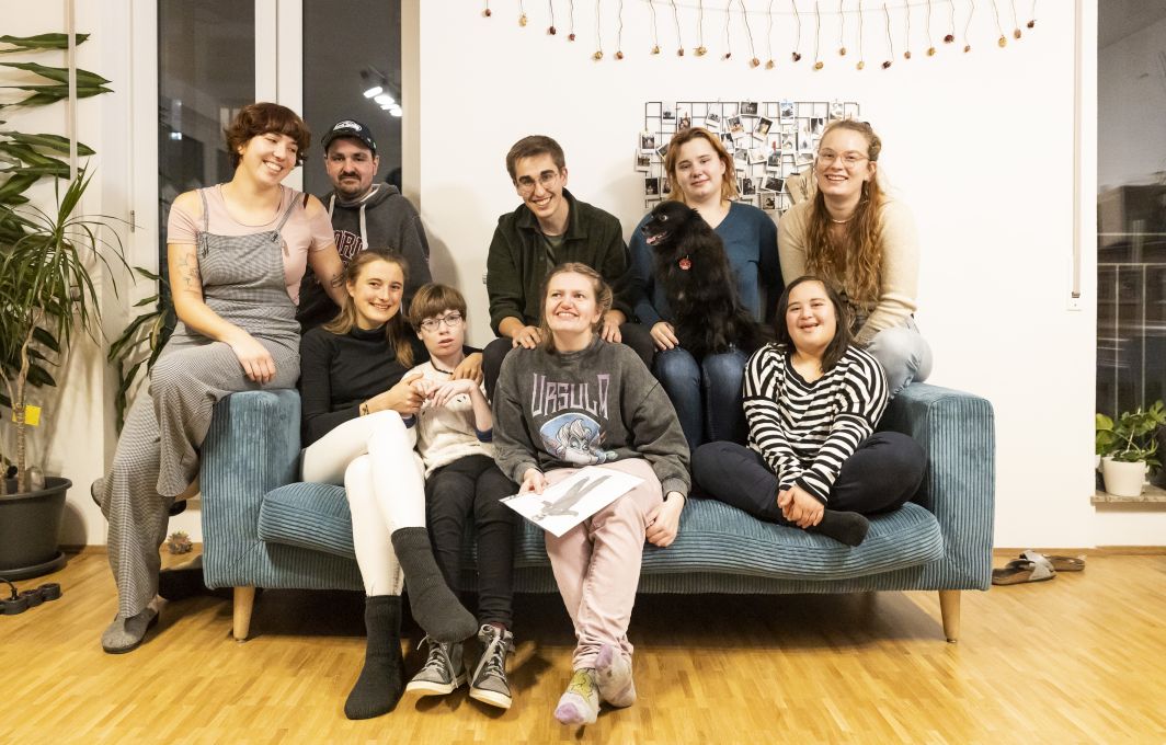 Die Mitglieder der WG sitzen für ein Gruppenfoto gemeinsam auf dem Sofa.