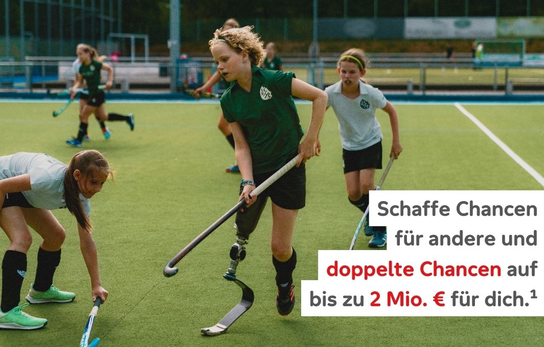 Mehrere Mädchen, eine von ihnen mit Beinprothese, spielen Feldhockey auf grünem Kunstrasen. Text: Schaffe Chancen für andere und doppelte Chancen auf bis zu 2 Mio. € für dich.