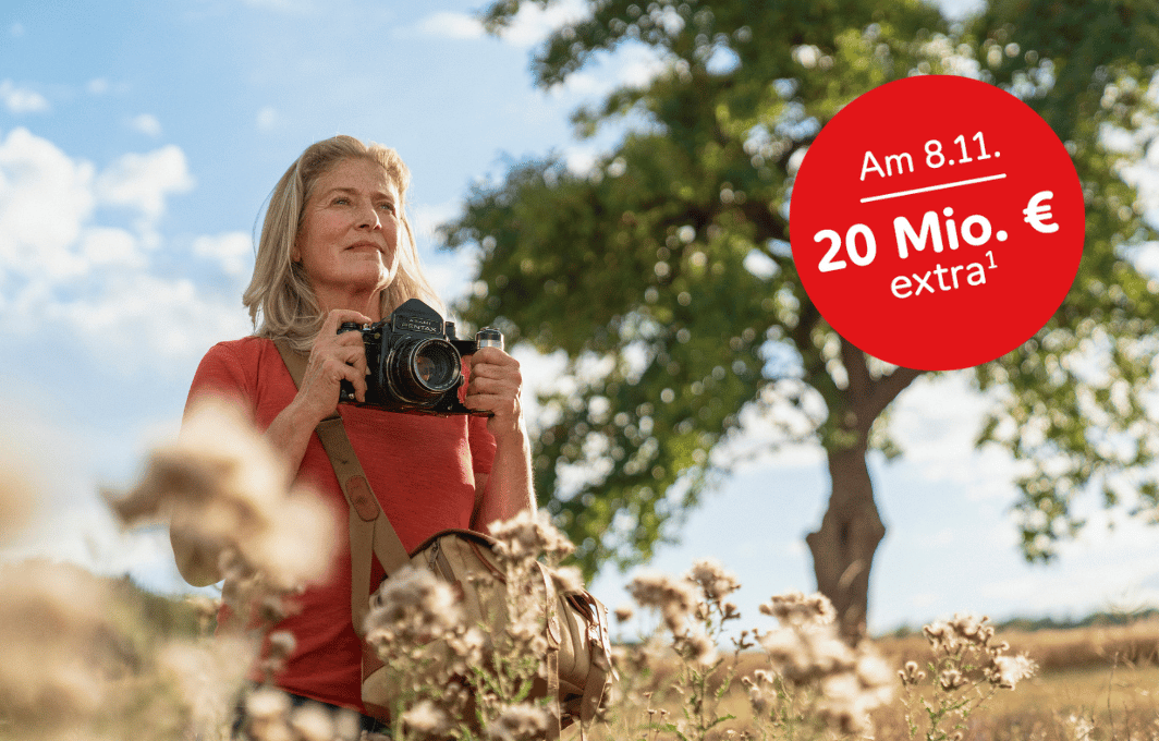Eine Frau steht mit ihrer Kamera auf einem Feld.
