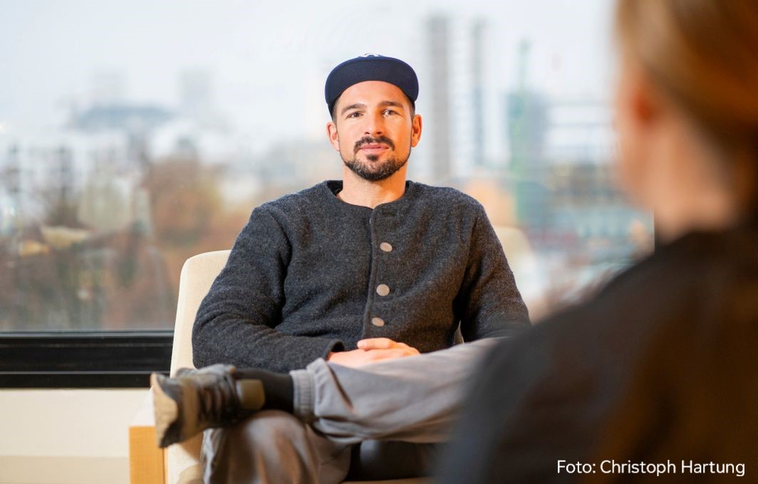 Benjamin Piwko sitzt in einem Sessel und ist im Gespraech mit der Interviewerin.