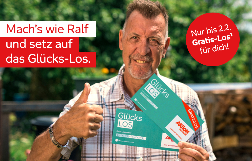 Ein Mann hält ein Glücks-Los und ein Gratis-Los in der einen Hand und zeigt mit der anderen einen Daumen nach oben.