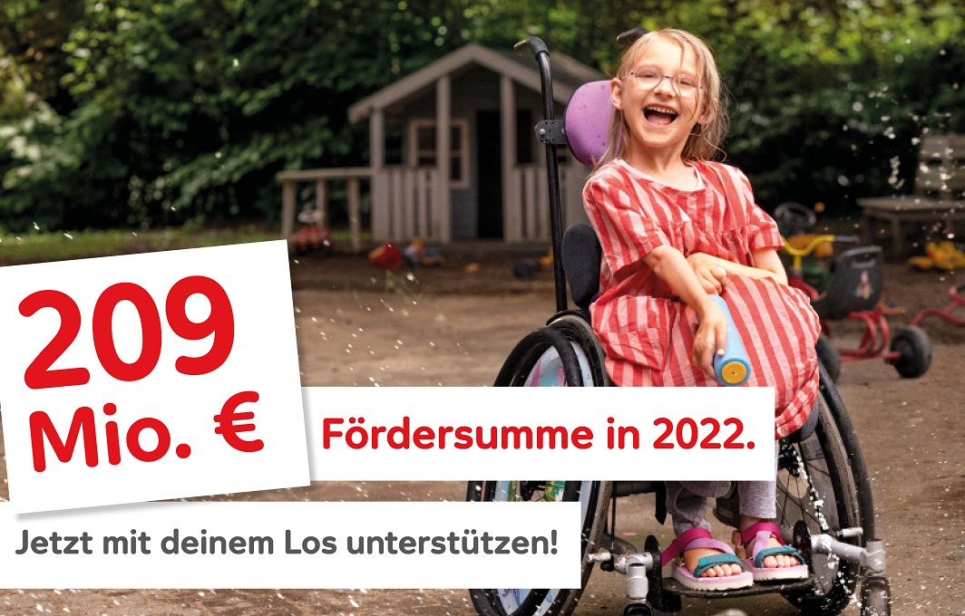 Ein Mädchen im Rollstuhl strahlt vor Freude.