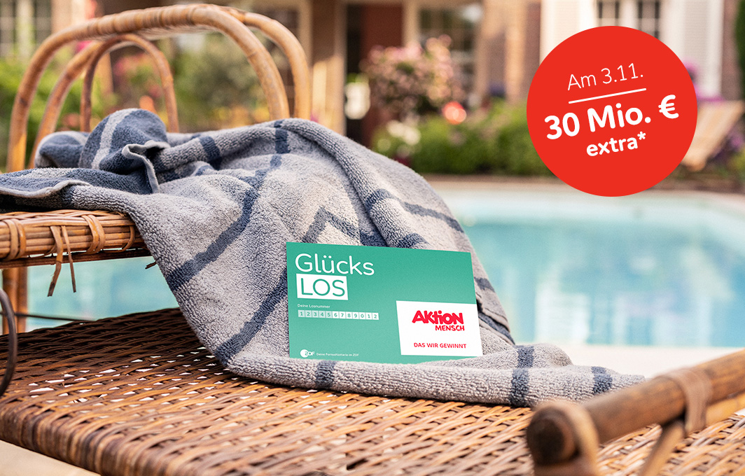 Ein Glücks-Los liegt auf einem Handtuch. Im Hintergrund ist ein Pool zu sehen.