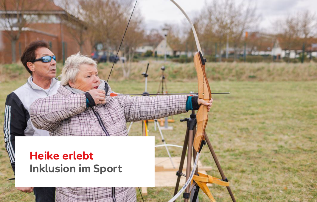 Heike hält einen Bogen mit Pfeil in der Hand. Hinter ihr steht unterstützend der Trainer.