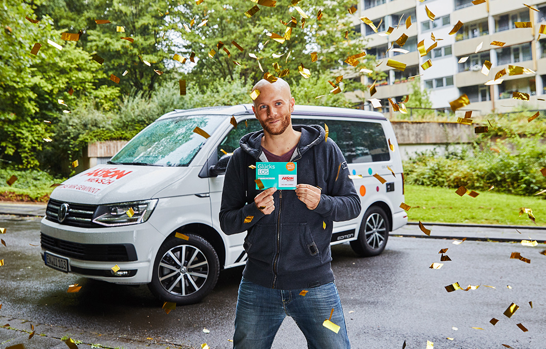 Unser Gewinner Lars hält sein Glücks-Los in die Kamera und freut sich. Von oben regnet Konfetti auf ihn.
