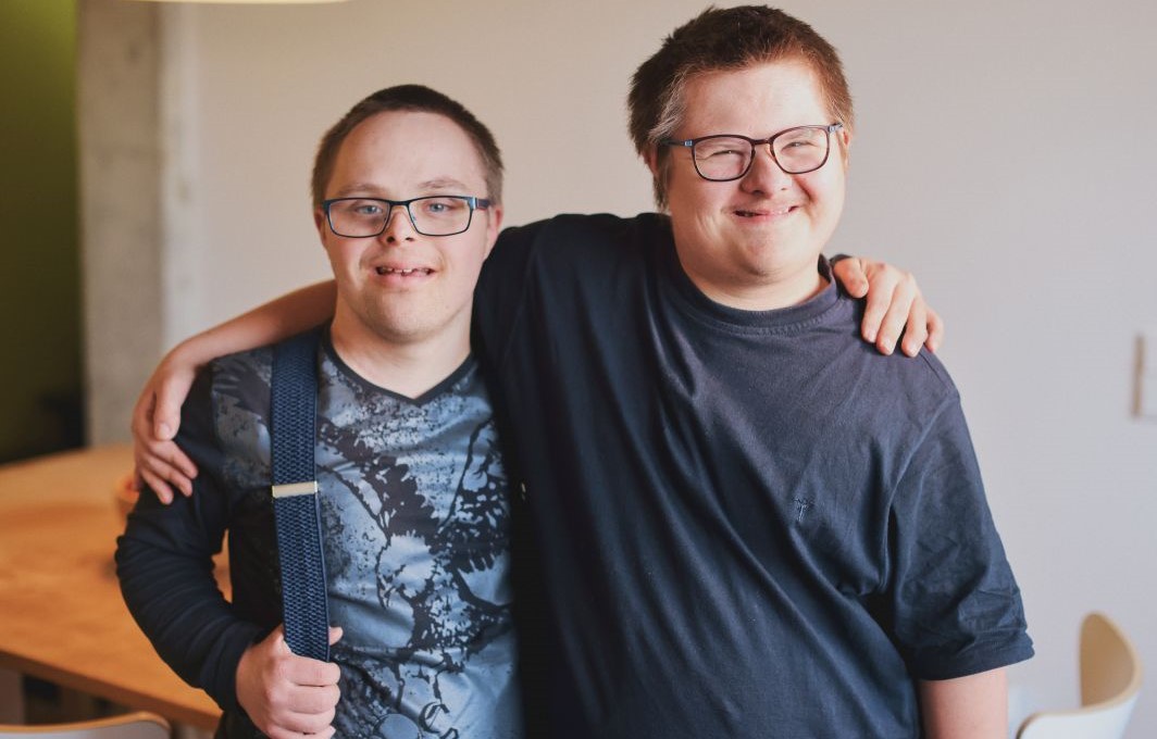 Max und ein weiterer Schüler der Wohnschule stehen lächelnd nebeneinander und haben jeweils einen Arm um die Schulter des anderen gelegt