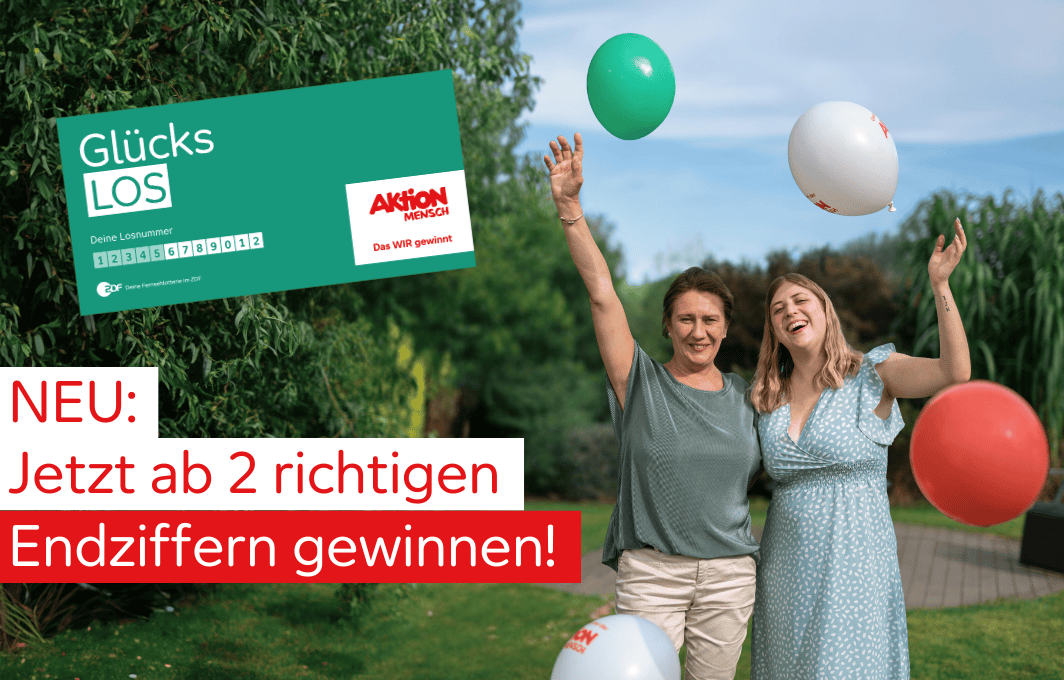 Zwei Frauen stehen jubelnd nebeneinander. Um sie herum fliegen Luftballons.