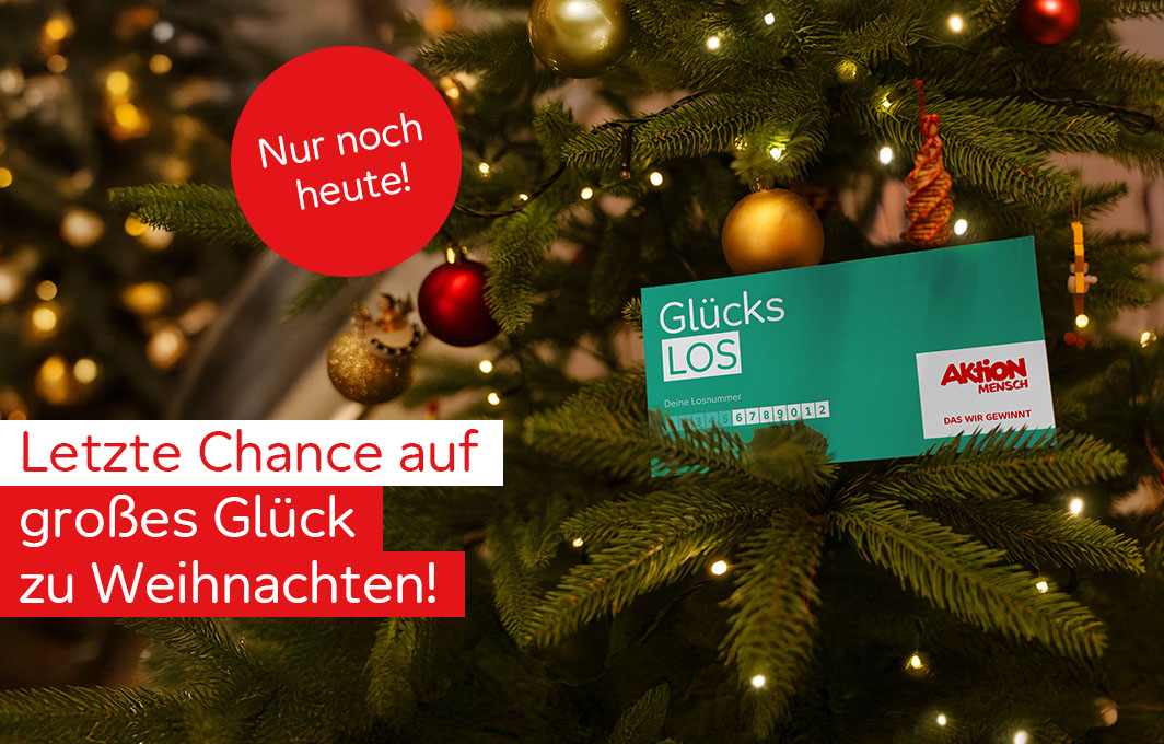Ein Glücks-Los hängt im Weihnachtsbaum.