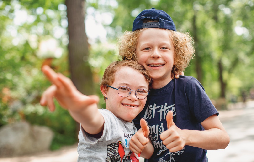 Ein kleiner Junge mit Downsyndrom ist mit seinem Freund auf dem Spielplatz.