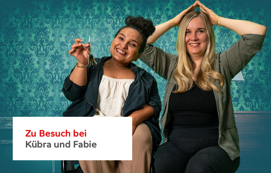 Kübra sitzt im Rollstuhl und hält einen Schlüsselbund in die Luft. Fabie formt mit ihren Händen ein Dach über ihrem Kopf.
