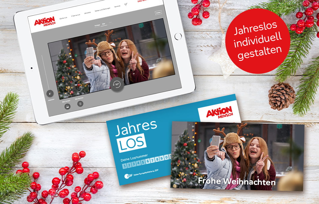 Ein Jahreslos mit eigenem Foto liegt auf einem weihnachtlich bedeckten Tisch.