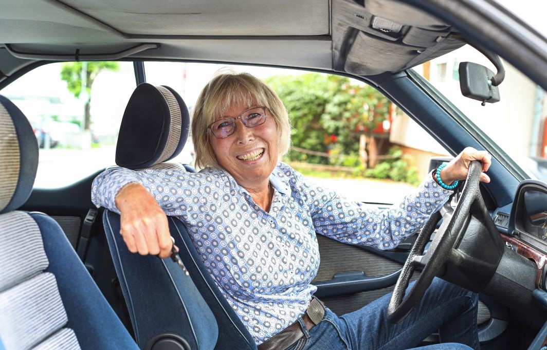 Gewinnerin Angelika sitzt mit fröhlichem Lachen in ihrem Auto.