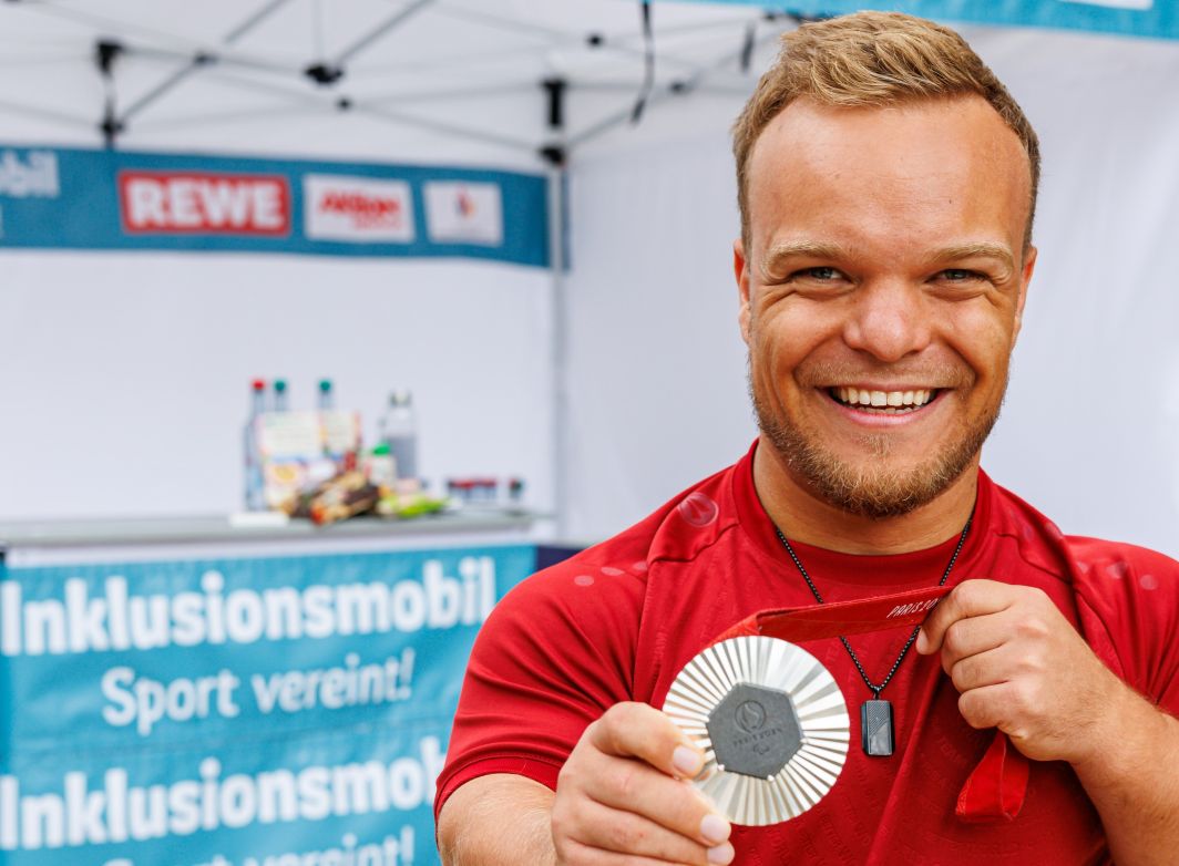 Para-Sportler Niko Kappel hält stolz seine Silbermedaille hoch, die er bei den Paralympischen Spielen 2024 gewonnen hat.