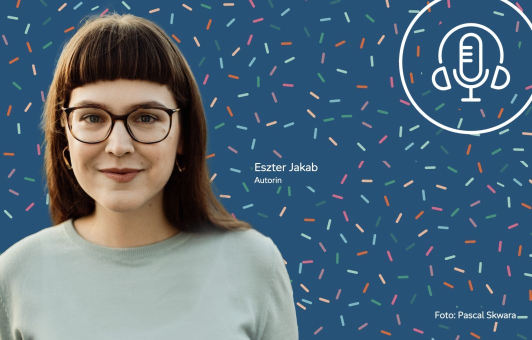 Porträt einer Frau mit Brille und langen dunklem Haar. Sie lächelt.